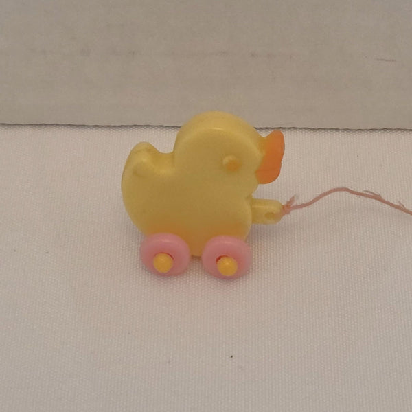 Yellow toy duck on wheels with a string, on a beige background