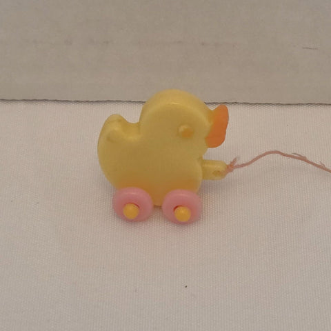 Yellow toy duck on wheels with a string, on a beige background